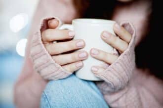 femme tenant tasse de café chaud et porte un pull en laine