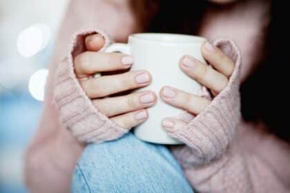 femme tenant tasse de café chaud et porte un pull en laine