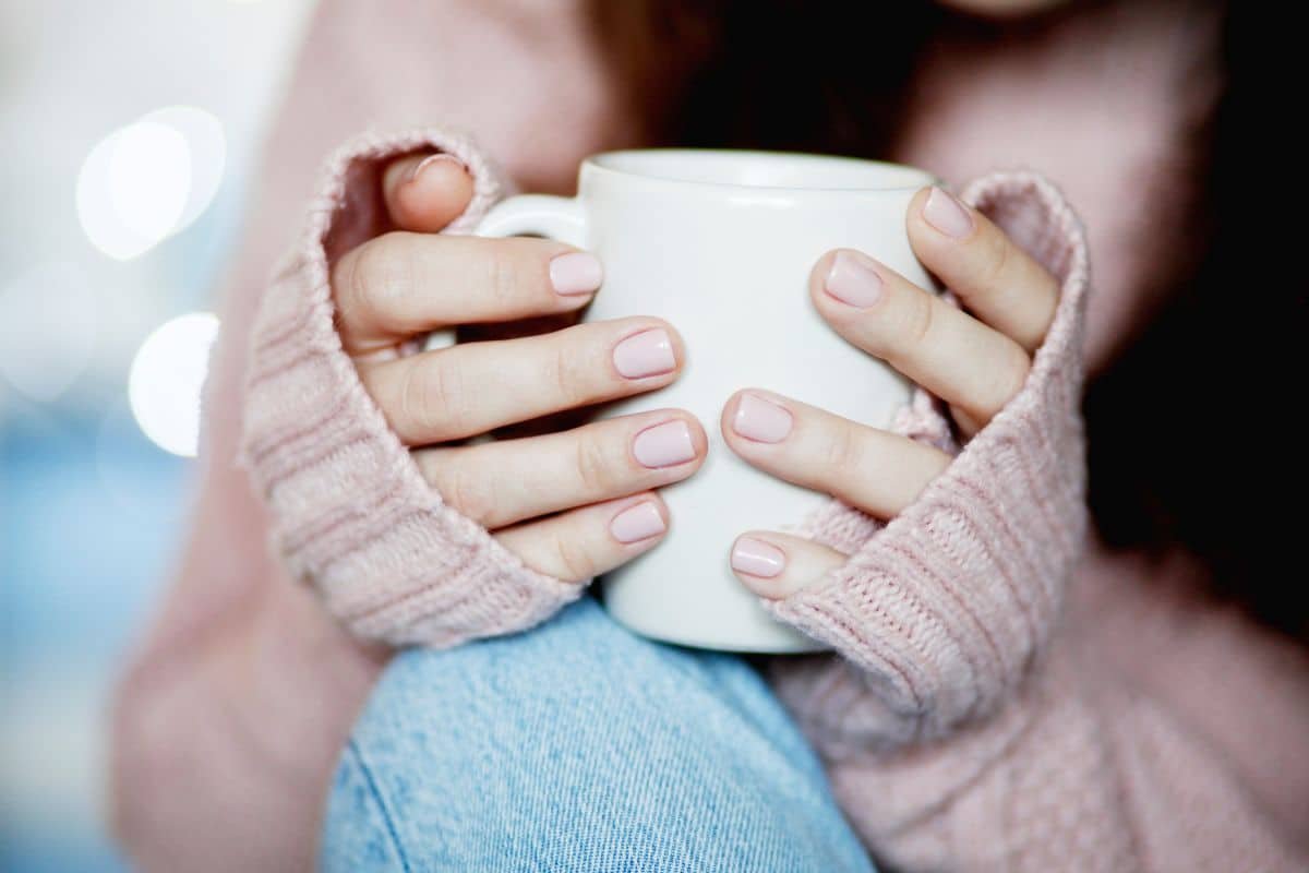 femme tenant tasse de café chaud et porte un pull en laine